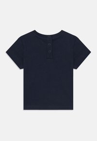 Marineblauwe korte mouwen T-shirt met een ronde hals en sluiting met drie knopen aan de achterkant. Gemaakt van zachte katoen met een gladde textuur.