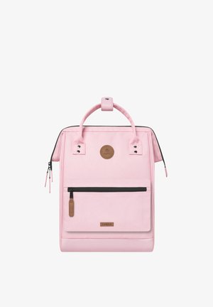 Pink backpack made of fabric with a smooth texture, featuring a front zip pocket, top handle, and a circular logo accent on the front.