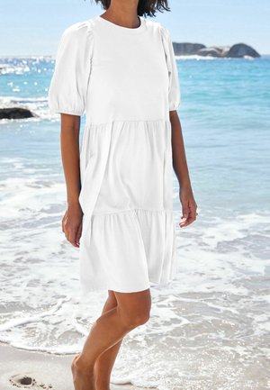 Vestido corto de algodón blanco con cuello redondo y dobladillo en capas, que presenta un corte holgado y mangas abullonadas fruncidas.