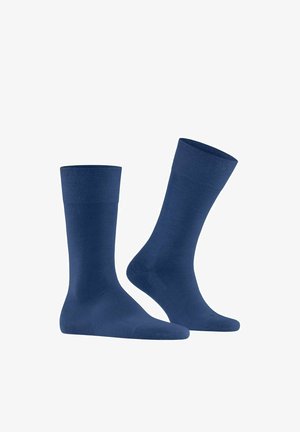 Paar schlichte marineblaue Kniestrümpfe, ein Strumpf steht aufrecht, der andere leicht nach vorne geneigt, isoliert auf weißem Hintergrund.