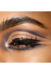 Close-up van een oog met gedurfde zwarte eyeliner en dikke wimpers. Oogschaduw bevat tinten bruin en brons met een rokerige afwerking.