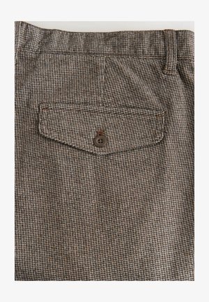 Pruun mustriga kangas väikese ruudustiku disainiga, kus on tagatasku pruuni nupuga. Sile tekstuur ja kohandatud sobivus.