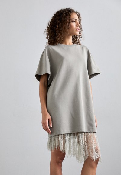 Üks suur hall puuvillane kleit lühikeste varrukatega, mille hemist leiab peene heleda pitsäärise, mis lisab tekstuuri ja kontrasti.