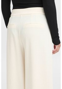 Witte textuur brede broek met een gladde tailleband, met twee achterzakken en een subtiel patroon voor extra detail.