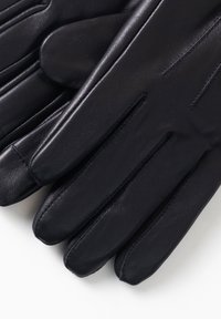 Guantes de cuero negro con un acabado liso, con un diseño clásico, dedos rectos y detalles de costura sutiles. Texturizados para un mejor agarre.