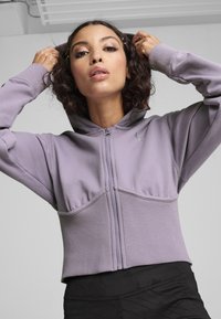 Felpa viola con zip, dal design aderente, orlo a costine e tasche a marsupio. Presenta un dettaglio del logo sul petto e un cappuccio.