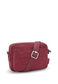 Lille burgunder crossbody taske med frontlomme, justerbar skulderrem og lynlåslukning på hvid baggrund.