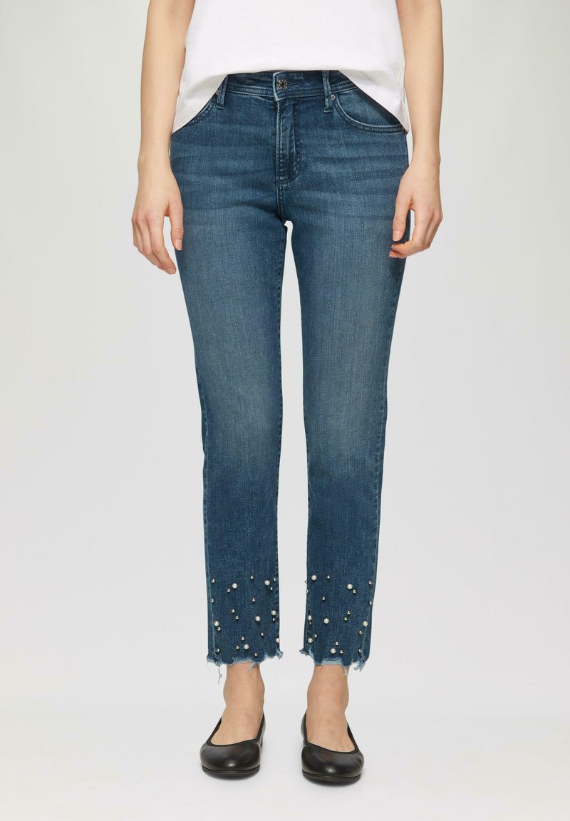 Jean en denim bleu à coupe droite, doté d'un ourlet effiloché orné de fausses perles blanches et d'un style classique à cinq poches.