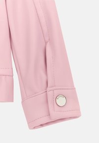 Różowa kurtka ze sztucznej skóry z rękawem o marszczonym wzorze przy łokciu i srebrnym guzikiem z logo. Gładka powierzchnia i dopasowany krój.