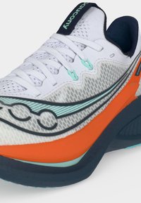 Λευκό αθλητικό παπούτσι με επάνω μέρος από δίχτυ, λογότυπο μάρκας σε χρώμα aqua και μαύρο, πορτοκαλί μεσαία σόλα και μαύρη επενδυμένη σόλα και αυχένα φτέρνας.