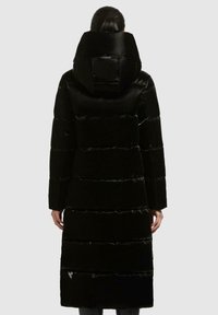Cappotto lungo e nero, imbottito, con colletto alto e cappuccio, caratterizzato da sezioni trapuntate e una finitura lucida. Include un dettaglio del logo sul lato.