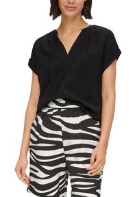 Schwarze kurzärmlige Bluse mit V-Ausschnitt, aus leichtem Stoff hergestellt. Kombiniert mit schwarz-weißen gestreiften Shorts mit elastischem Bund.