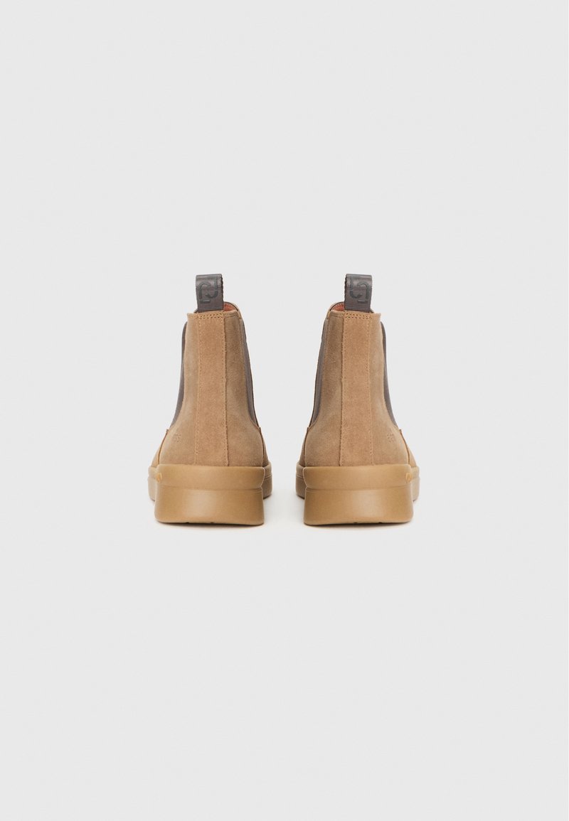 Stivali ankle in camoscio marrone con pannelli laterali elasticizzati e suola in gomma. Il retro presenta un'etichetta scura e una silhouette aerodinamica.