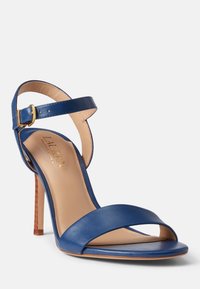 Blå läderhögklackad sandal med ett enstaka rem över tårna, vristrem med guldspänne och en beige innersula.