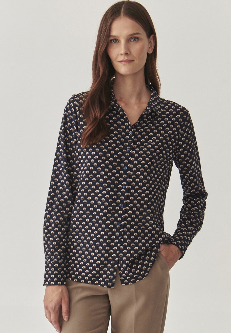 Camicia blu navy con motivo floreale in crema e rosa chiaro, con maniche lunghe e colletto classico. Tessuto di texture liscia.