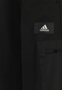 Schwarze Sportshorts mit glatter Textur, ausgestattet mit einer seitlichen Reißverschlusstasche und einem rechteckigen Adidas-Logo in Weiß.