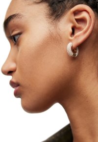 Guldtonade hoopearringar prydda med små vita pärlor, med en böjd design som omfamnar örsnibben.