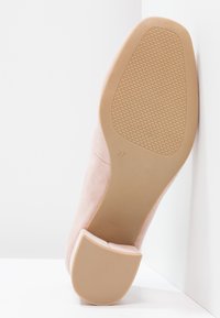 Scarpa in suede rosa pallido con punta arrotondata e tacco basso a blocco. La suola è beige con un motivo di grip testurizzato, taglia 37 indicata di lato.