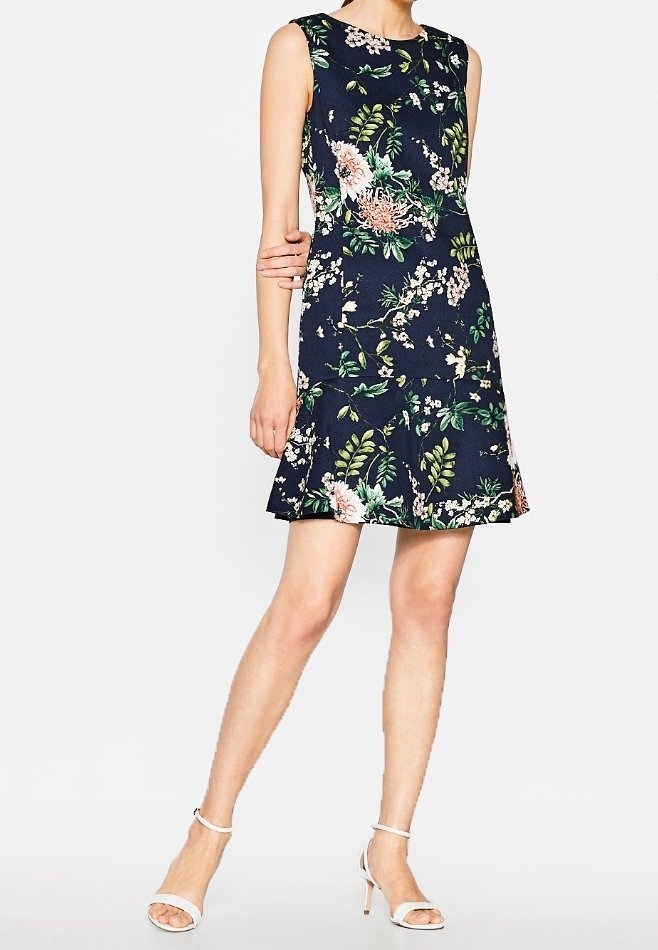 Šaty s květinovým vzorem na tmavě modrém pozadí, bezrukávový design, rozšířený lem a bílé akcenty. Mají kulatý výstřih a hladkou texturu.