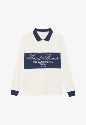 Long-sleeve polo shirt, cream and navy, cotton blend. Features a navy band with white text, and a classic collar with navy trim.