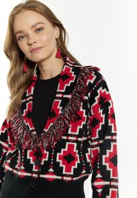 Cardigan a motivo rosso, nero e bianco con colletto frangiato, chiusura con bottoni e maniche lunghe, realizzato in materiale a maglia.