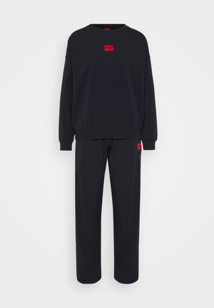 Sweatshirt noir et pantalon assorti en tissu doux. Présente un logo rouge brodé sur la poitrine et une petite étiquette similaire sur le pantalon.