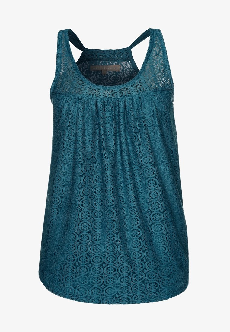 Haut sans manches en dentelle teal avec des motifs circulaires, devant froncé et bretelles en mode caraco.
