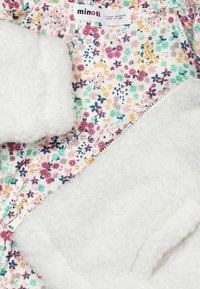 Látka s květinovým vzorem v pastelových barvách s bílou plyšovou podšívkou. Obsahuje zapínání na zip a měkké, texturované prvky pro teplo.