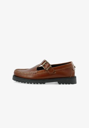 Bruine leren schoen met een uitgesneden ontwerp, voorzien van een decoratieve gesp en een contrasterende zwarte rubberen zool met een gestructureerd loopvlak.