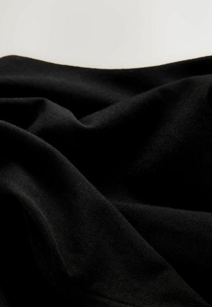 Svart tyg draperat i veck, med en slät struktur och jämn yta, som har ett mjukt utseende och en svag lyster under ljus.