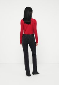 Red ribbed long-sleeve top paired with black high-waisted jeans. The jeans feature a straight leg design and back pockets.