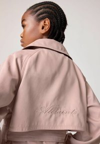 Bordeauxfärgad kort jacka i slätt tyg, med en bred krage och en broderad "Allsaints"-logotyp på baksidan.