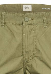Khaki spodnie wykonane z miękkiego materiału, z zapięciem na guzik, kieszeniami z przodu i widocznymi szwami. Metka informuje "Camel Active" i "REGULAR."