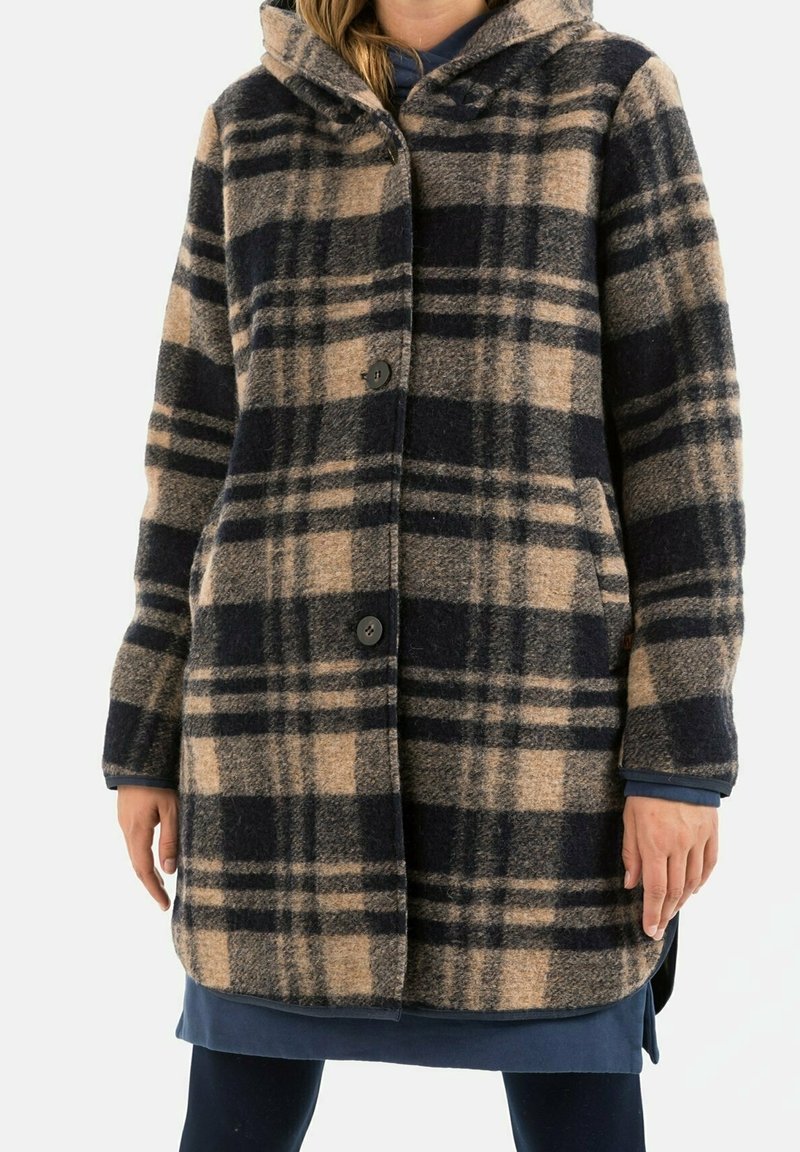 Geverfd wollen jas met een capuchon, in beige en donkerblauw, met drie knopen en zijzakken. Geweven stof met een zachte afwerking.