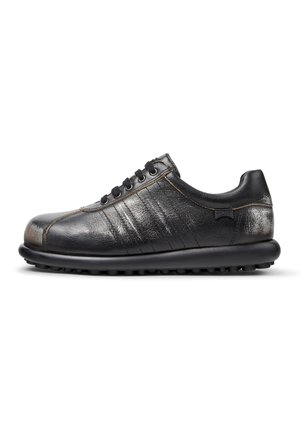 Sneaker in pelle nera a taglio basso con chiusura frontale a lacci, punta arrotondata e suola spessa e strutturata, mostrata di profilo su sfondo bianco.