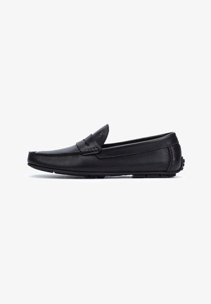 Mocasines de cuero negro con un diseño de perfil bajo y sin cordones, que cuentan con una puntera cosida y detalles texturizados en el empaque. Acentos de suela de goma.