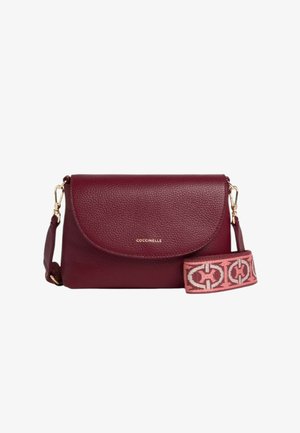 Sac bandoulière en cuir bordeaux avec un rabat arrondi, des ferrures dorées et une sangle en tissu à motifs rose et crème. Logo de la marque embossé à l'avant.