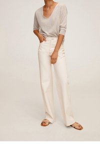 Light gray V-neck sweater with three-quarter sleeves, paired with high-waisted, wide-leg cream jeans. Neutrally colored sandals complete the look.