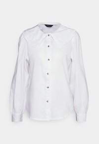Camisa branca de botão, com um grande colarinho franzido, mangas longas e botões de pérola na frente. Feita de um tecido leve.