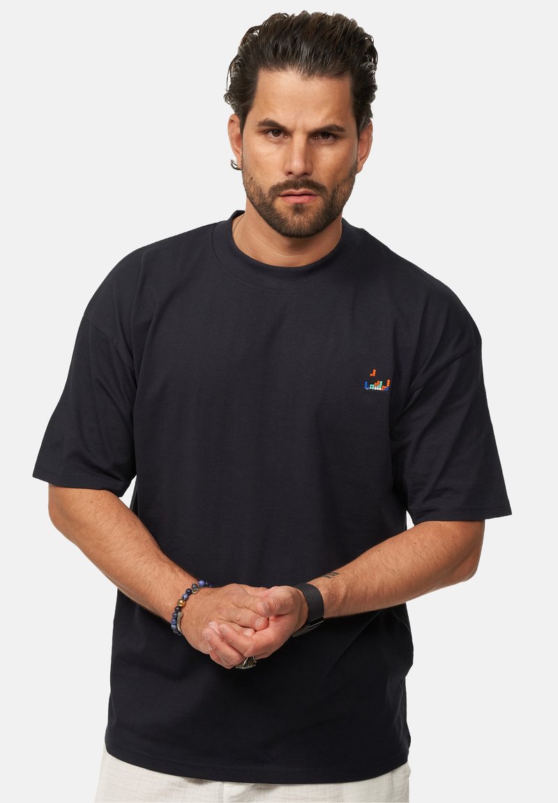 Navyblaues Baumwoll-T-Shirt mit kurzen Ärmeln, versehen mit einem kleinen, auf der Brust gestickten Logo. Lockerer Schnitt und Rundhalsausschnitt.