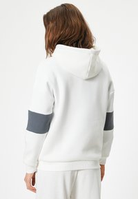 Witte hoodie met een grijze horizontale streep op de mouwen. Voorzien van een trekkoord capuchon en ribgebreide manchetten en zoom. Zachte, gestructureerde stof.