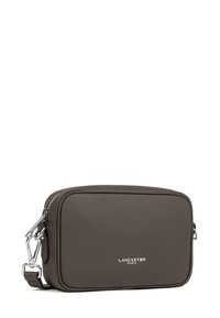 Borsa a tracolla in pelle marrone con chiusura a zip. Presenta un logo argentato sul davanti e una tracolla regolabile. Texture liscia, forma rettangolare.