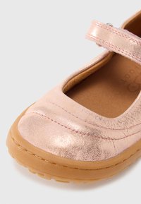 Ροζ μεταλλικό δερμάτινο παπούτσι με στρογγυλή μύτη, ραφές και ταμπά καουτσούκ σόλα. Διαθέτει λουράκι βέλκρο για ασφαλή εφαρμογή.