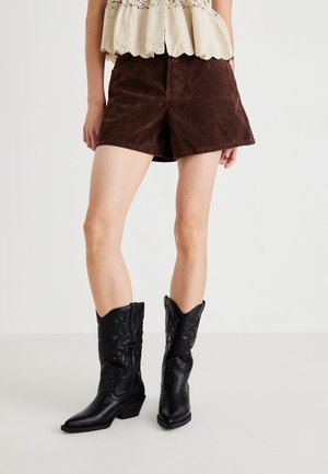 Black leather cowboy boots with pointed toes and low block heels, featuring intricate stitching and silver hardware accents.