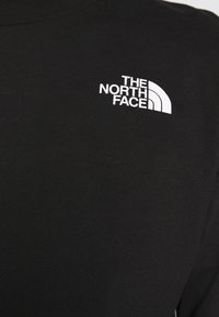 Svart långärmad t-shirt i bomull med rund halsringning. Har en vit broderad logotyp av "THE NORTH FACE" på vänster bröst.