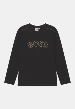 Chemise noire à manches longues avec col arrondi, surpiqûres jaunes contrastantes aux épaules et "BOSS" imprimé en grandes lettres contournées sur la poitrine.