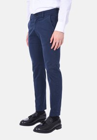 Pantaloni chino blu navy in cotone, con vestibilità slim, tasche anteriori e chiusura a bottone. Abbinati a scarpe da dress nere e calzini.