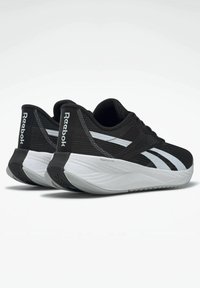 Zapatillas deportivas negras con una parte superior de malla transpirable, acentos blancos y una suela gruesa y acolchada de color blanco con un patrón texturizado.