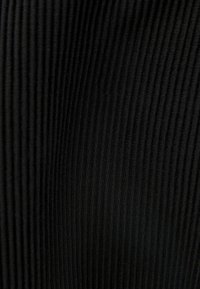 Černá tkanina s vertikální žebrovanou texturou, která ukazuje jemné linie a měkký materiál. Celkový vzhled je hladký a konzistentní.