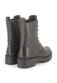 Botas tobilleras de cuero marrón con superficie texturizada, cierre de cremallera y suelas de goma reforzadas con un patrón de dibujo.